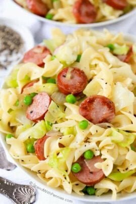 Cabbage and Noodles in a bowl with peas and sausage topped with pepper