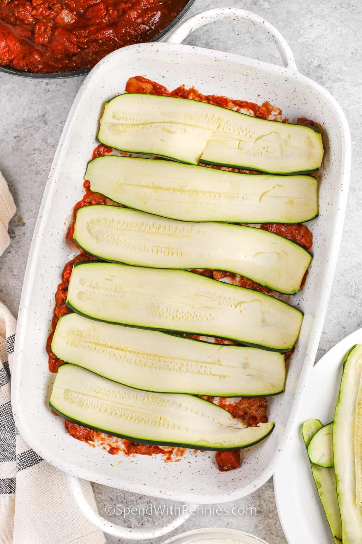 adding zucchini slices to dish to make Zucchini Lasagna