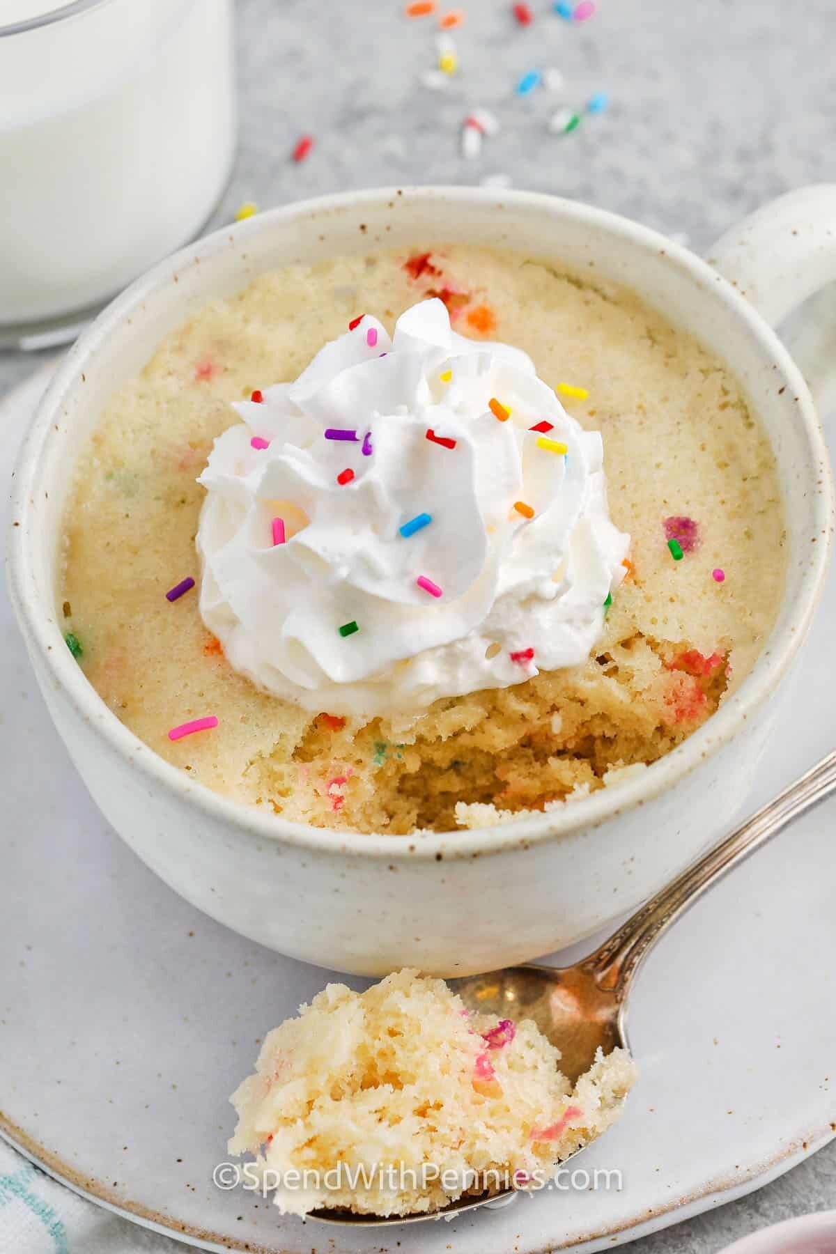 Vanilla Mug Cake with whipped cream and sprinkles with a portion taken out