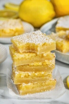 Five lemon bars stacks on top of each other with a bite taken out of the top